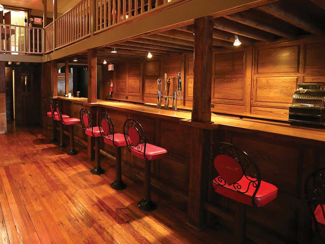 Red cushioned bar chairs line a wooden bar