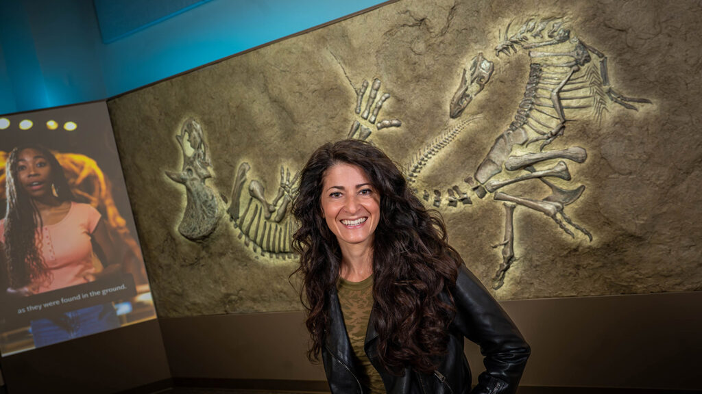 Lindsay Zanno stands in front of a replica block of the Dueling Dinosaurs.