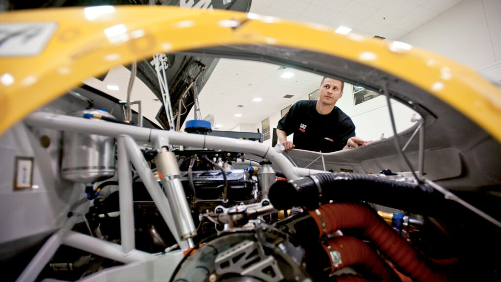 Alumnus Luke Lambert looks through a car he has to help guide in competition on Sundays in NASCAR.