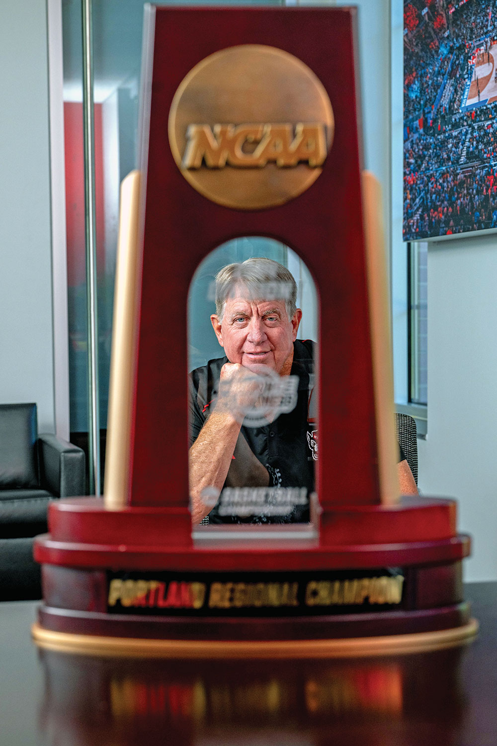 An NCAA trophy, in the foreground, frames Wes Moore's face.