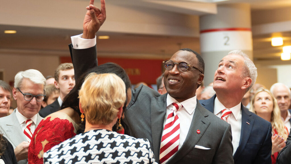 Kevin Howell makes the "Wolfie" hand gesture to students in attendance at his introduction ceremony inside of Talley.