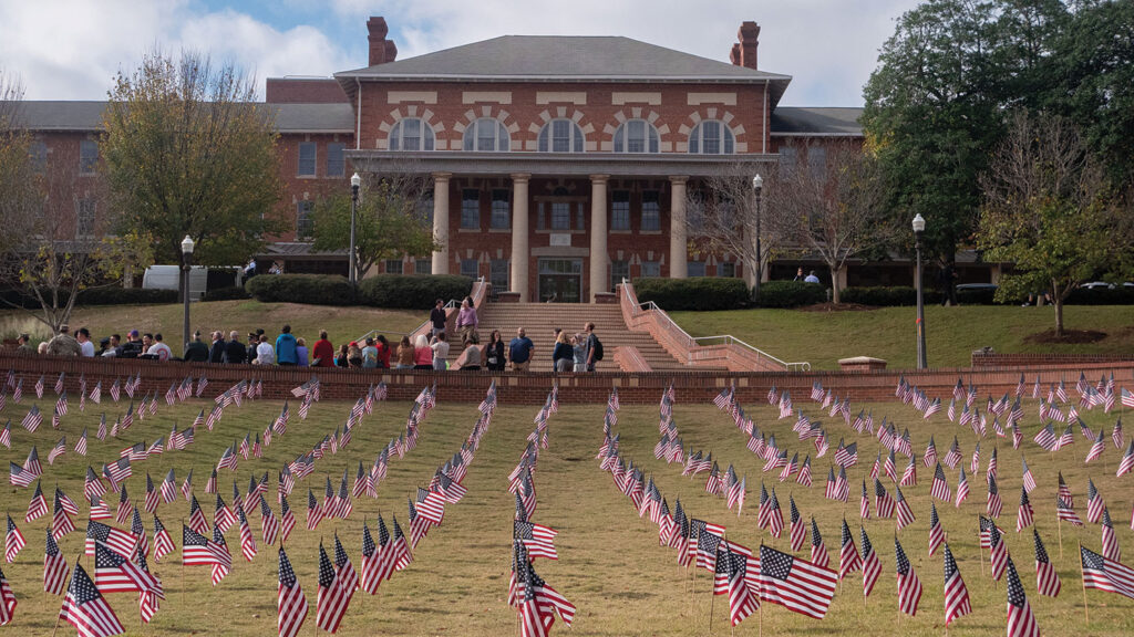 Veterans Day flag display at NC State Court of North Carolina with hundreds of American flags covering the lawn in front of the 1911 building, a historic brick university building, as community members observe the memorial tribute.