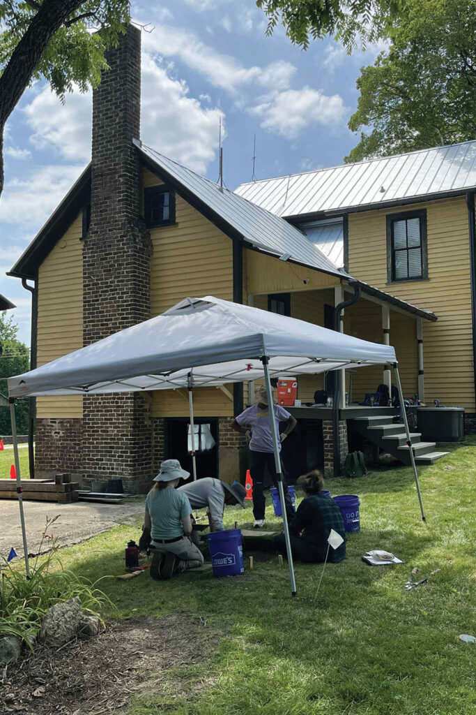 Archaeology students work under a tent at Glencoe Mill Village