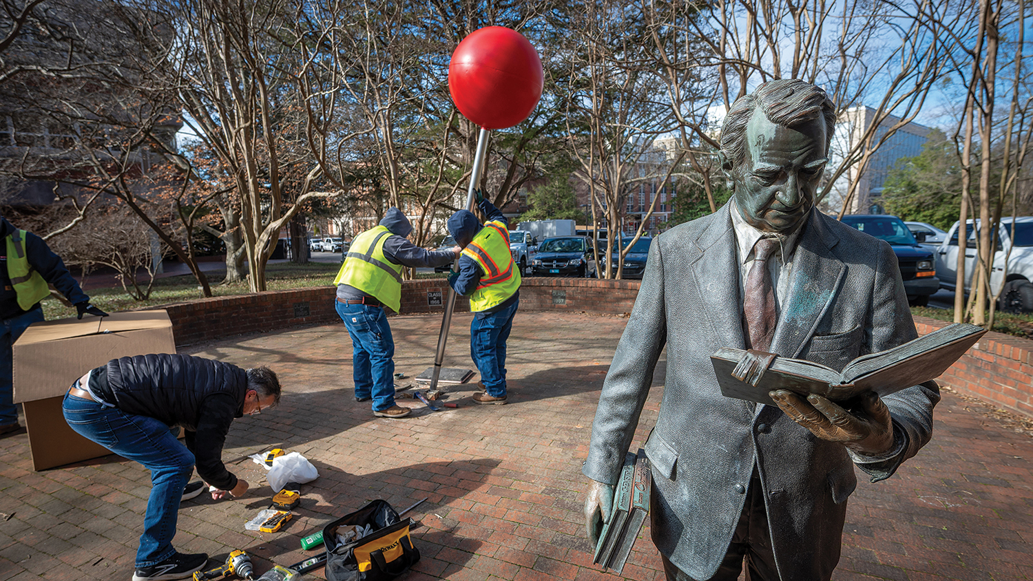 Installation of red pins on campus behind Walking Professor statue